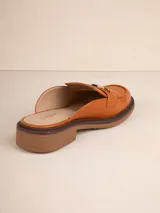 Mocasín tipo mule (abierto en el talón) de símil cuero negro, con suela de plataforma gruesa y taco bajo. Presenta un detalle de cadena metálica dorada sobre el empeine.