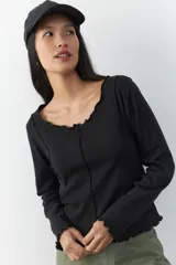 Remera blanca de manga larga con cuello redondo y costuras a la vista.