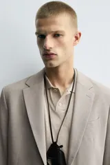 Blazer slim fit de color beige, confeccionada en tejido con lana. Presenta cuello con solapas de muesca, cierre frontal con un botón, bolsillos con solapa en la cadera y bolsillo de vivo en el pecho.