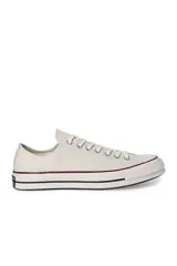 Championes Converse Chuck 70 Ox de lona color crema con suela de goma blanca y detalles en azul y rojo.