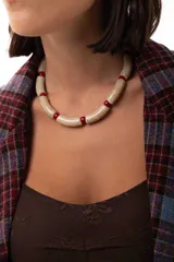 Collar corto tipo gargantilla compuesto por cuentas cilíndricas de efecto craquelado en tono crema intercaladas con pequeñas cuentas esféricas de color rojo.