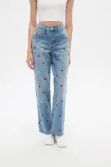 Pantalón jean de tiro alto y corte recto, color azul claro, con bordados de pequeños corazones rojos y rosados en toda la prenda.
