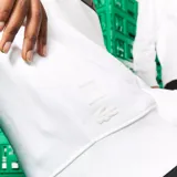 Buzo blanco de algodón con cuello redondo y mangas largas. Estampado frontal con el logo de Lacoste pixelado en verde y rojo, y el logo de Minecraft debajo.