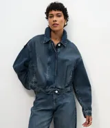 Campera bomber de jean azul oscuro, de corte corto con mangas globo, cuello con solapa y cierre frontal abotonado.