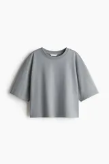 Remera gris de corte cuadrado y holgado, con cuello redondo y mangas cortas anchas. Confeccionada en tejido de punto suave de algodón.