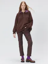 Buzo oversize de algodón color marrón, con cuello polo y cierre frontal parcial. Presenta bolsillos laterales con cierre y cuello forrado en seda color violeta.