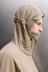 Chaqueta de hombre color marrón óxido con textura de pequeños cuadrados en relieve. Presenta cierre frontal de cremallera, capucha ajustable, bolsillos laterales con solapa y puños ajustables. El interior es de forro polar.