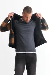 Campera con capucha, forrada en piel sintética, con cierre frontal y diseño a cuadros grandes en tonos verde y negro.