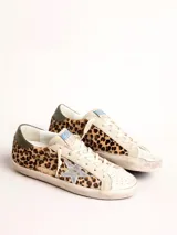 Zapatillas Golden Goose modelo Super-Star, con estampado animal print de leopardo, estrella plateada en el lateral y detalle verde en el talón.