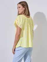 Blusa amarilla con textura labrada, escote redondo elastizado y mangas cortas con aberturas y lazos.