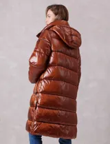 Campera puffer larga de abrigo marca BCBG Maxazria, color beige. Cuenta con capucha desmontable, cuello alto envolvente, cierre frontal bidireccional con solapa de botones a presión, bolsillos laterales, puños internos elastizados y tajos laterales con cierre en el bajo.