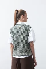 Chaleco tejido de algodón y acrílico, color rojo y blanco con patrón geométrico. Tiene cuello redondo y bordes acanalados en rojo.