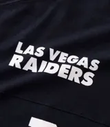 Remera de corte oversized confeccionada en algodón, con diseño deportivo inspirado en el equipo de fútbol americano Las Vegas Raiders. Presenta cuello redondo, mangas cortas con detalle de rayas horizontales y estampado gráfico frontal con el logo del equipo y la inscripción Raider Nation.