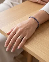 Pulsera elástica compuesta por pequeñas piedras naturales cúbicas de color azul profundo, intercaladas con cuentas metálicas plateadas.