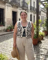 Chaleco blanco de algodón con bordados botánicos en negro, escote en V y cierre frontal con lazo.