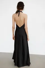 Vestido largo de satén con cuello halter y escote fluido. Presenta un diseño de espalda descubierta con cierre de cremallera oculta y lazada ajustable en el cuello.