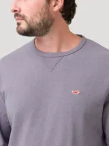 Buzo de algodón orgánico color gris jaspeado, con cuello redondo y terminaciones en rib en cuello, puños y pretina. Presenta un pequeño parche bordado de un pato en el pecho.