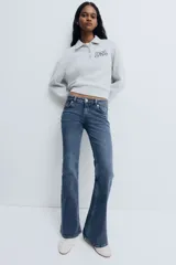 Jean de denim elástico color azul con efecto deslavado, tiro bajo, corte ajustado hasta la rodilla y diseño acampanado. Cuenta con cierre de botón y cremallera, bolsillos delanteros y bolsillos traseros con solapa y botón.