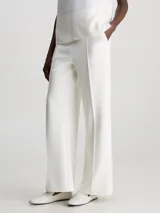 Pantalón blanco de pierna ancha confeccionado en tejido de punto técnico con poliéster reciclado y elastano. Presenta talle medio, pinzas delicadas en el centro de la pierna, bolsillos con ranura y barra de metal con logo de Calvin Klein debajo de la cintura.