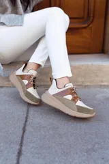 Championes deportivos de cuero en tonos marrón, tostado y marrón oscuro, con detalles de estampado animal print de leopardo en el lateral, suela gruesa blanca y cordones elásticos.