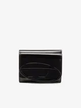 Billetera compacta de tres pliegues confeccionada en cuero vacuno con acabado espejado. Presenta un diseño minimalista en color negro con el logo ovalado de la marca en relieve al tono en la parte frontal. Incluye ranuras para tarjetas, compartimento para billetes y bolsillo para monedas.