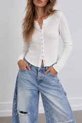 Blusa de punto color celeste con textura waffle, manga larga y cierre frontal de botones metálicos.