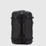 Mochila urbana de diseño técnico y minimalista en color negro, con capacidad de 28 litros. Presenta un compartimento principal con cierre central, correas de compresión laterales con hebillas, manijas de transporte reforzadas y el logo de la marca estampado en el frente. Fabricada en material repelente al agua.
