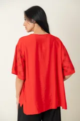 Blusa negra de viscosa con estampado de flores blancas en las mangas, corte holgado, cuello redondo y botones frontales.