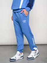 Pantalón deportivo azul claro con puños ajustados en los tobillos. Presenta el escudo del Club Nacional de Football bordado en la pierna izquierda y el logo de Umbro bordado en la derecha.