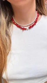 Collar corto doble, uno con perlas pequeñas y otro con piedras rojas irregulares y una perla central.