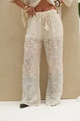 Pantalón beige con bordado floral en relieve, corte recto y cintura elástica.