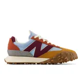 Championes New Balance unisex modelo XC-72, con capellada de gamuza color mostaza, detalles en celeste, bordó y naranja, logo "N" en bordó, entresuela blanca y suela marrón con diseño de tracción agresivo.