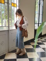 Cartera bandolera de cuero color camel, con forro interno de tela y flecos laterales.