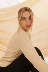 Buzo de tejido de punto color beige con lurex plateado, de cuello alto y mangas largas.