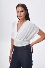 Top blanco con cuello drapeado y mangas cortas.