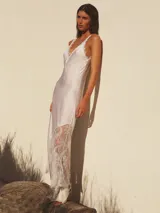 Vestido largo blanco de seda con escote en V y detalles de encaje en el bajo y escote.