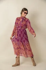 Vestido midi plisado de gasa estampada en tonos violeta y naranja, con lazo en el cuello y en la cintura.