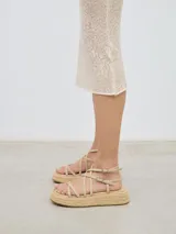 Sandalia con plataforma de esparto, tiras delanteras a diferentes niveles y cierre con hebilla al tobillo.