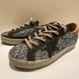 Zapatillas plateadas con glitter, detalles en cuero gris y cobre patinado, plantilla de 17 mm, suela y banda de caucho.