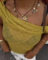 Collar corto de estilo artesanal, compuesto por una variedad de piedras naturales en tonos tierra, verdes, rojos y amarillos, intercaladas con pequeñas perlas de río. Presenta dijes de bronce macizo con formas orgánicas, incluyendo una figura de pez y un dije circular central, unidos por un cierre de barra y argolla.