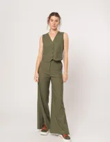 Pantalón negro de lino, tiro alto, corte palazo, con elástico en la pretina trasera, cierre delantero y broche interno. Tiene bolsillos laterales, dobladillo invisible y tajos a los costados.