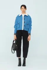 Chaqueta azul con bolsillos delanteros forrada, botones metálicos y cuello desmontable con corderito.