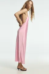 Vestido largo color rosa pálido, con escote en V pronunciado y tirantes finos tipo espagueti que se unen en la espalda. El corte es recto y holgado, con caída fluida.