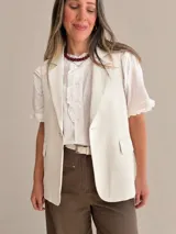 Chaleco sastrero color beige con solapas clásicas, bolsillos con solapa y cierre frontal con un botón.