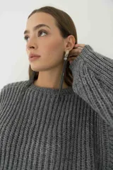Sweater de punto grueso color gris, con cuello redondo y mangas anchas.