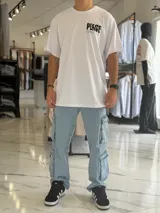 Remera oversize blanca de manga corta, con gran estampado negro en la espalda con la palabra 'Peace' y símbolos gráficos.