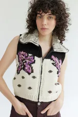 Chaleco de tejido de punto con cierre frontal, cuello solapa y diseño estampado con motivos florales en tonos violeta, negro y crudo.