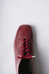 Zapato acordonado de cuero color negro, de diseño minimalista con punta cuadrada y silueta moderna.
