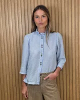 Camisa de algodón color blanco, con cuello alto con volados, mangas tres cuartos con detalles de bordado ingles y cierre frontal con botones de nácar.