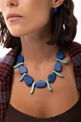Collar corto compuesto por cuentas de piedra reconstituida en tonos azul profundo y turquesa claro, con diseño alternado de piezas planas y alargadas. Incluye cadena de extensión de acero quirúrgico.